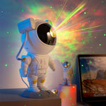 Astronaut lamp projecting colorful lights on a wall with a laptop in the background.