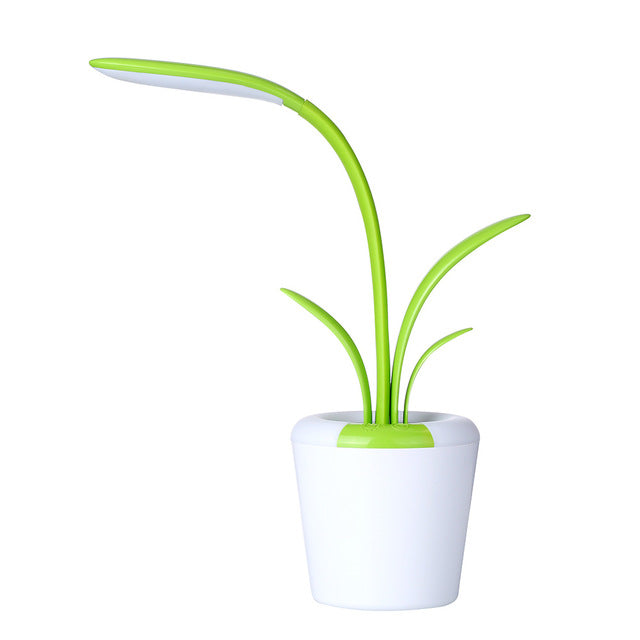 Green plant-shaped desk lamp with white base on a white background