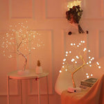 Decorative LED trees on small tables with a warm glow against a neutral wall.