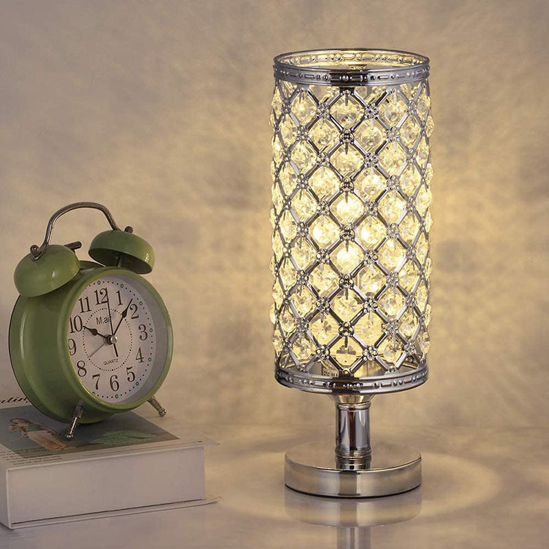 Decorative table lamp with crystal design next to a green alarm clock on a neutral background