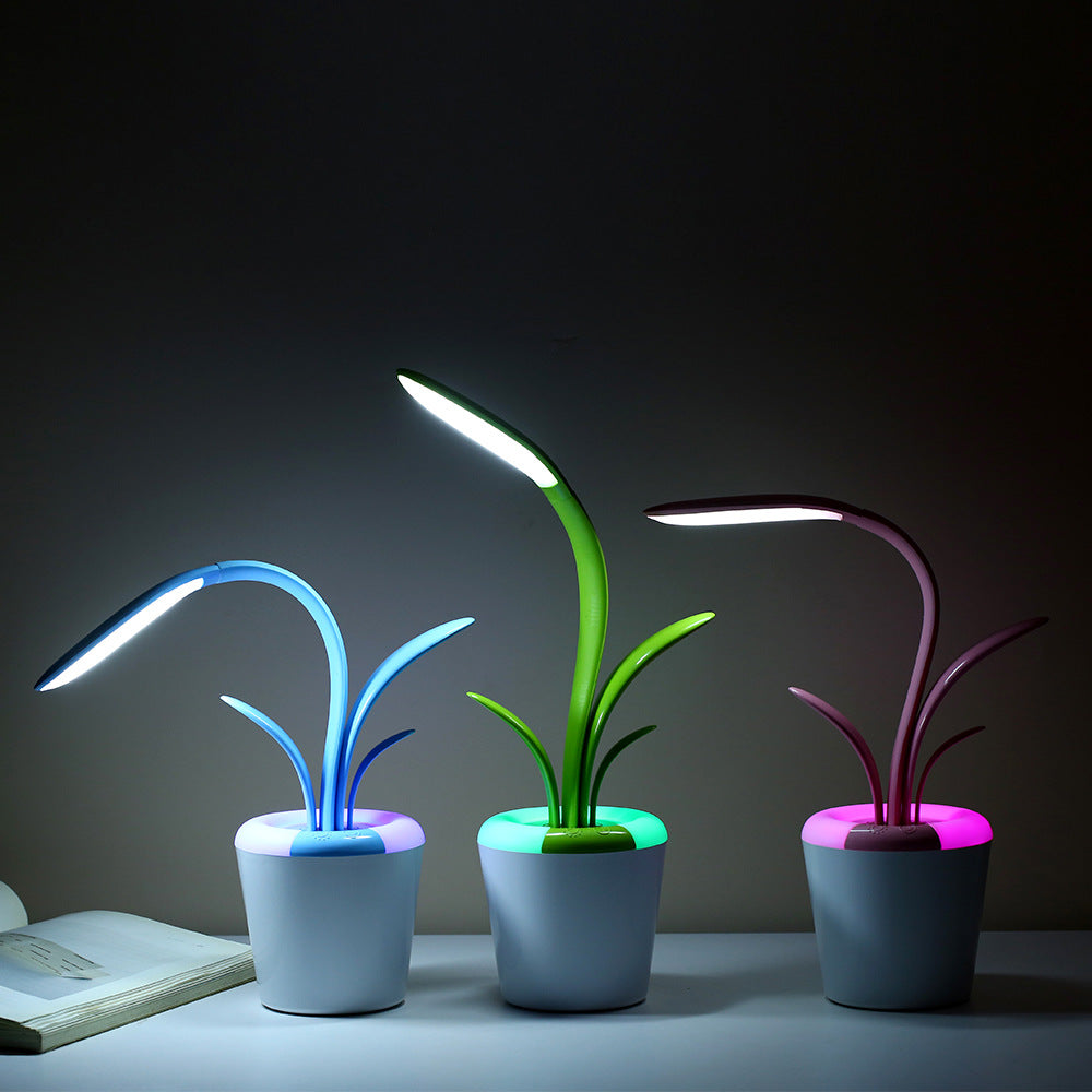 Three LED desk lamps with plant designs on a dark background