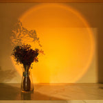 Vase with flowers on a wooden surface with a warm light casting a circular shadow on the wall.