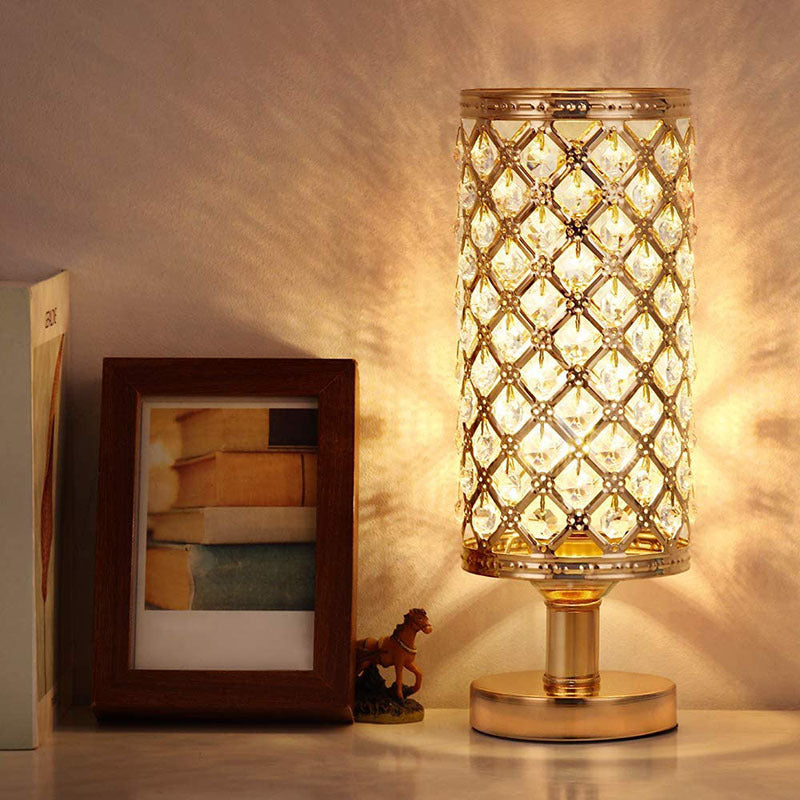 Decorative table lamp with intricate design on a surface next to a photo frame and small figurine.