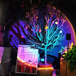 Decorative tree with colorful lights in a room with a screen and plants