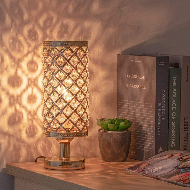 Decorative lamp on a table with books and a plant in the background