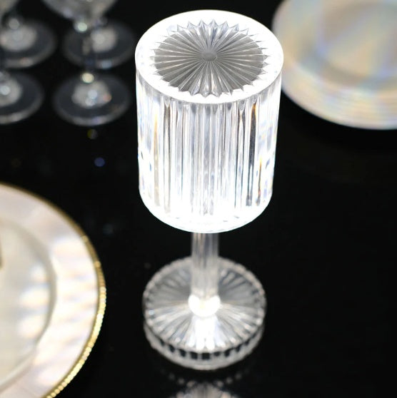 Clear crystal candle holder on a reflective surface with blurred background