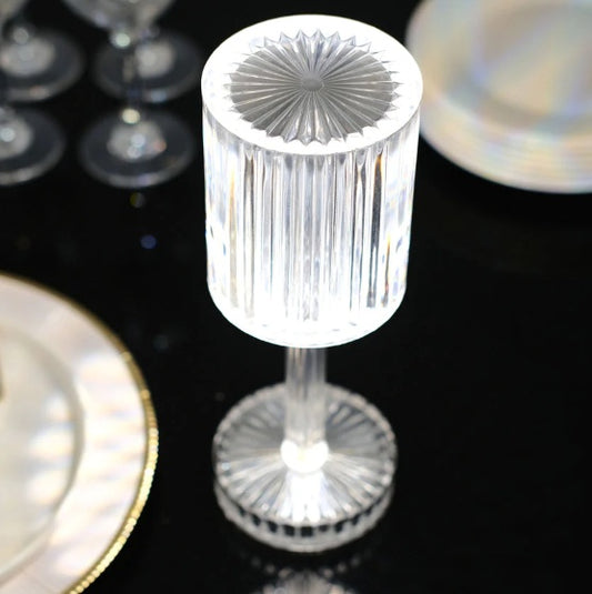Clear crystal candle holder on a reflective surface with blurred background