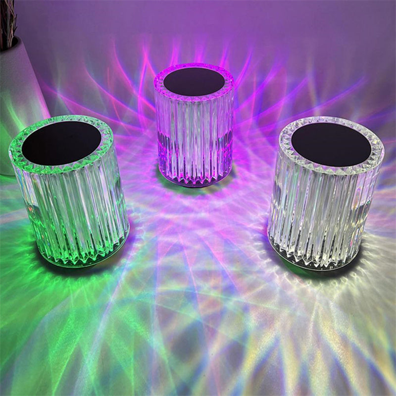 Three colorful LED cylindrical lights on a reflective surface with vibrant light patterns.