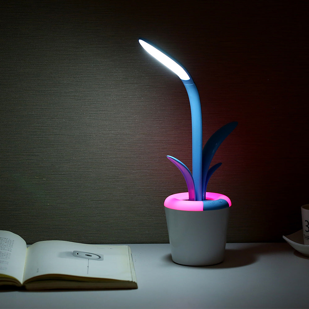 Desk lamp with plant design on a table next to an open book