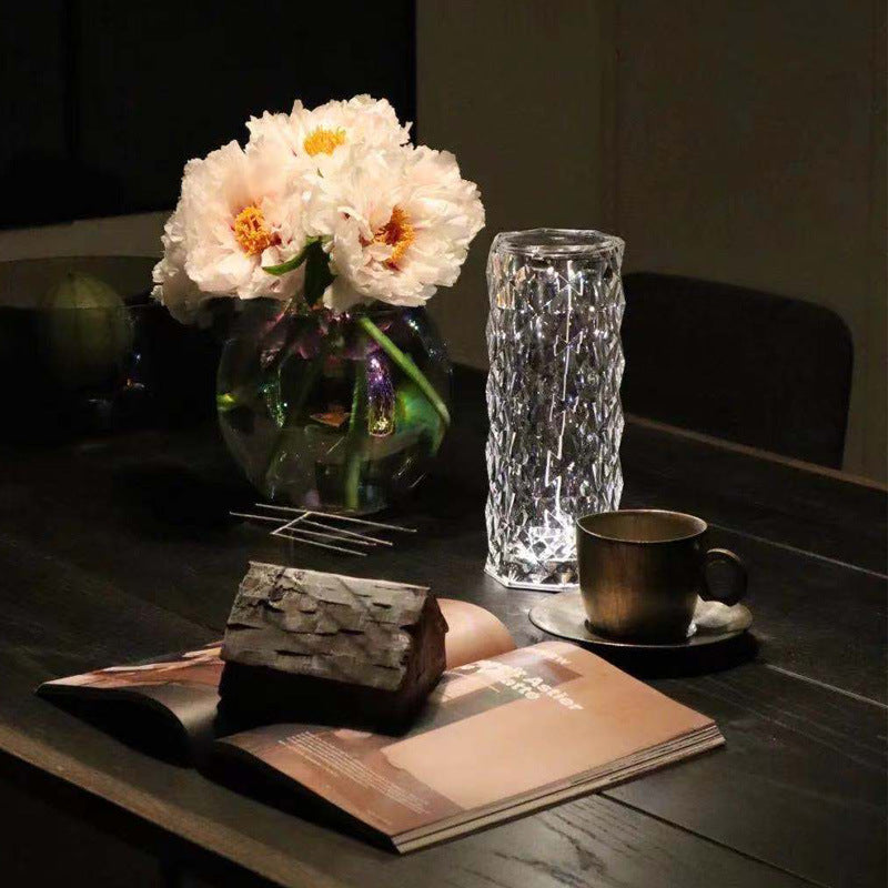 Table setting with flowers, a cup, and a magazine on a dark surface.